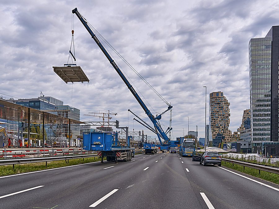 Kraan hijst een perronkap over de volledig afgesloten A10 Zuid bij station Amsterdam Zuid